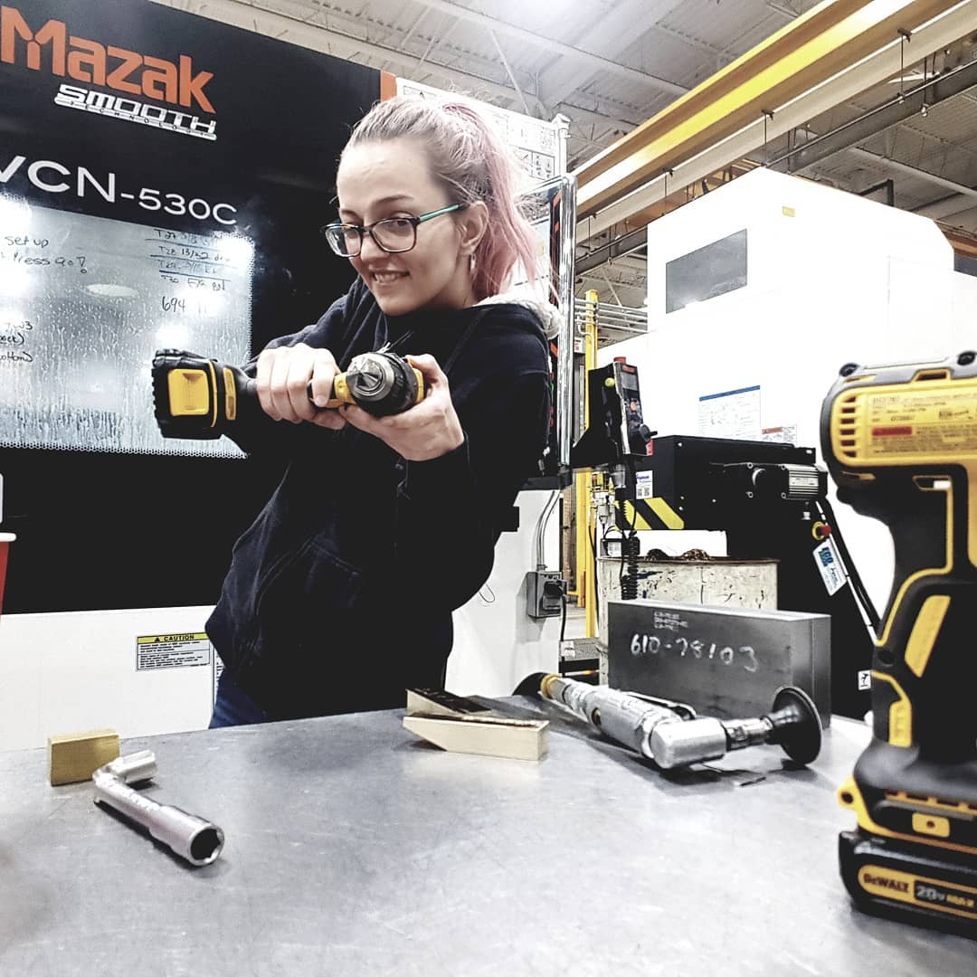 Rebecca Chenier holding a drill outside of her machine at Centreline