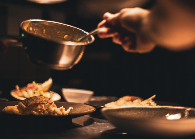 A chef dishing up food into plates.