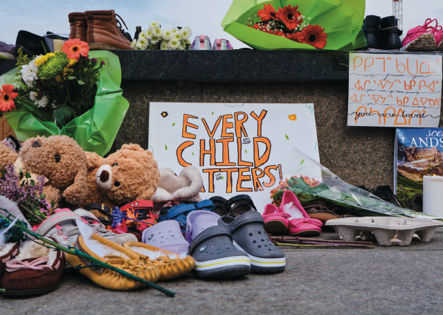 Photo from Parliament Hill showing flowers and shoes and a sign that says, "Every Child Matters".