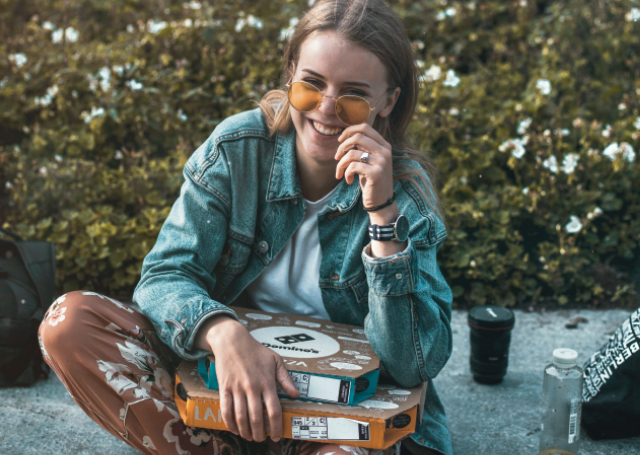 Woman sitting with pizza boxes on her lap.